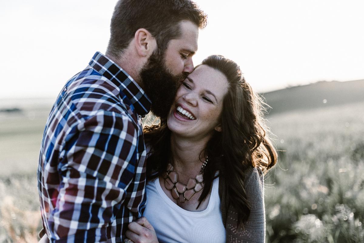 Man Kissing Girlfriend In Field